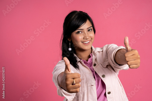 asian woman showing thumb up over pink background