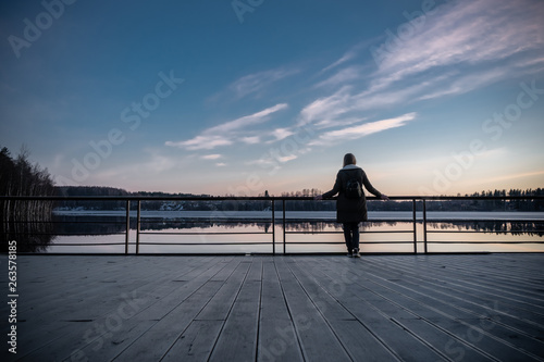 beautiful sunset, the girl stands on the bridge , in the Harbor, watching the sunset, the water reflected clouds