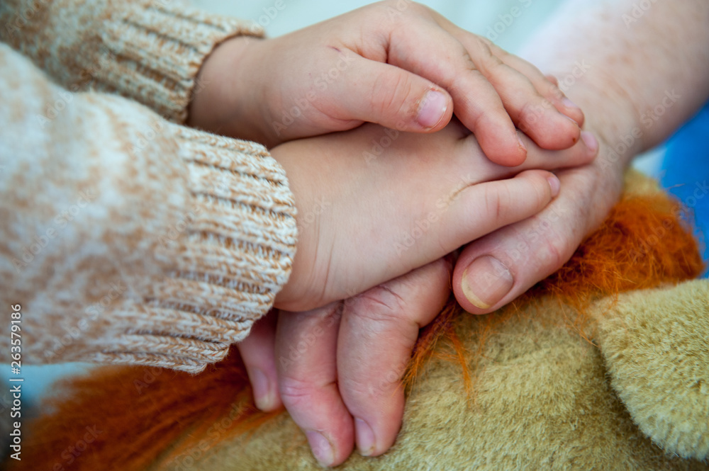 Hands close up. Elderly woman sits and plays with her grandson on couch. Child is very fond of grandmother. Boy kiss and hug his beloved grandmother. Hands close up. Elderly woman sits and plays with her grandson on couch. Child is very fond of grandmother. Boy kiss and hug his beloved grandmother.