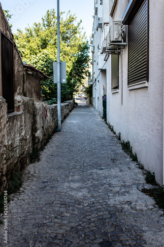 a narrow urban street with stone floors and old vintage buildings