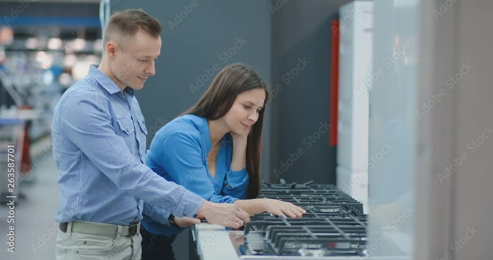 Young couple chooses cooktop in store of household appliances Young couple chooses cooktop in store of household appliances