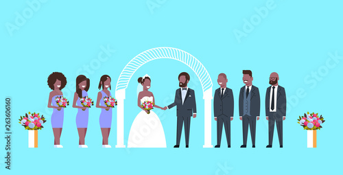 just married bride and groom with african american bridesmaids groomsmen standing together near arch wedding ceremony concept blue background full length horizontal flat