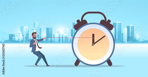 businessman pulling clock arrow deadline time management concept business man in suit pushing back hour hand modern city buildings cityscape background horizontal flat full length
