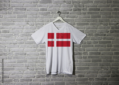 Denmark flag on white shirt and hanging on the wall with brick pattern wallpaper photo