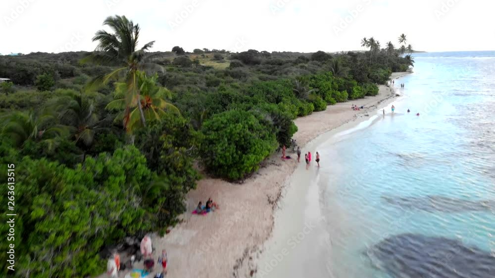 Jaw dropping fast paced drone shot over a white sand beach towards a vast green countryside