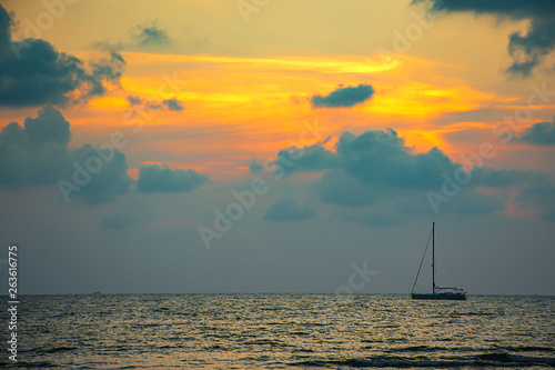 Yacht parked in the sea and the sun behind the clouds in the evening.