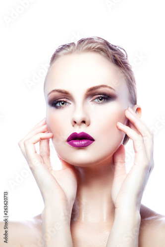 Beauty fashion model woman studio portrait with bright purple lipstick make-up  clean skin  hair style and hands touching face. Isolated. White background