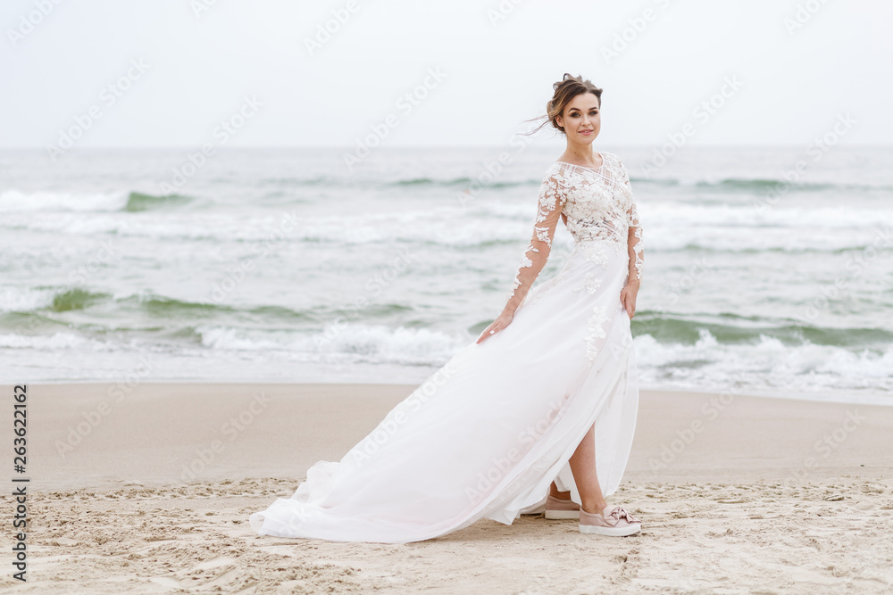 positive bride runs on the sea beach on an overcast day