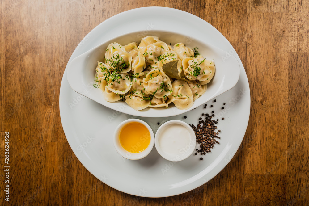 Meat dumplings or pelmeni served with sour cream and dill