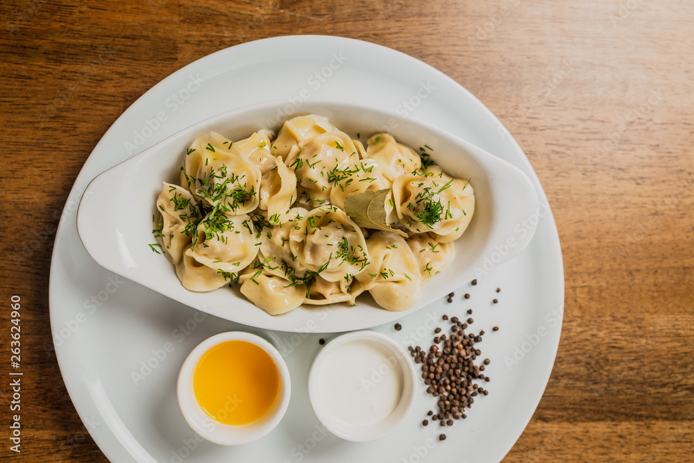 Meat dumplings or pelmeni served with sour cream and dill Meat dumplings or pelmeni served with sour cream and dill