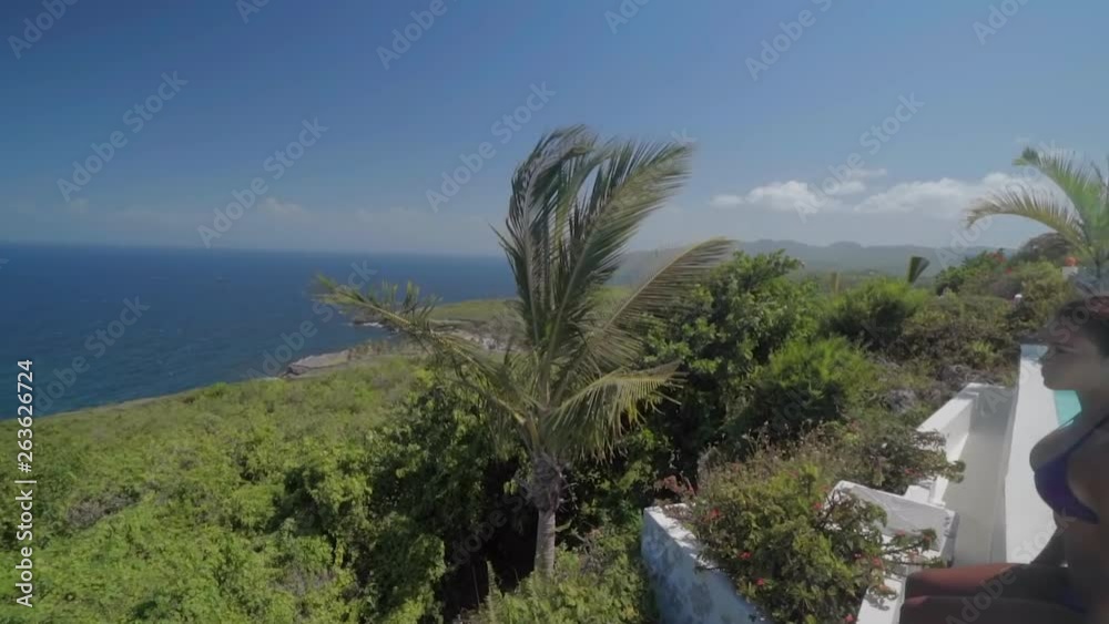 Slow Motion: Young Woman in Bikini Sitting on Pool Wall Overlooking Ocean in El Limon, Dominican Republic Slow Motion: Young Woman in Bikini Sitting on Pool Wall Overlooking Ocean in El Limon, Dominican Republic