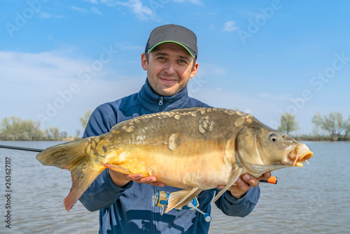 Fishing backgrounds. Fisherman with carp fish in hands.