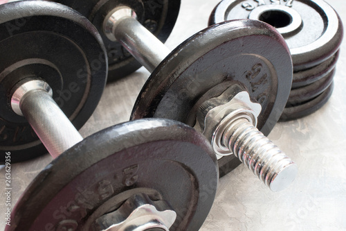 Fitness or bodybuilding concept background. Product photograph of old iron dumbbells on grey, conrete floor in the gym.
