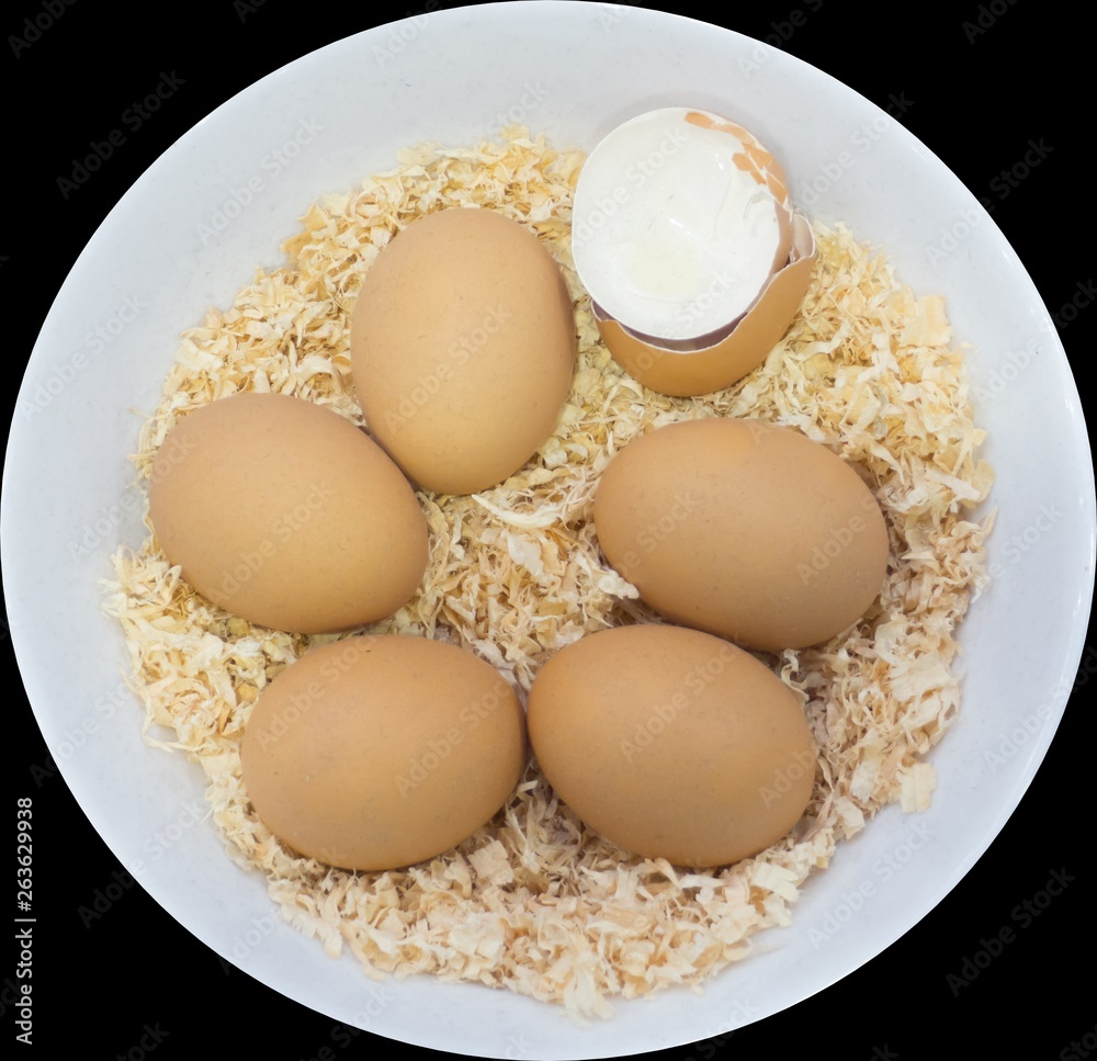 Six brown eggs on brown Sawdust with one being crack egg, which they are in a round white bowl, isolated on black background. Six brown eggs on brown Sawdust with one being crack egg, which they are in a round white bowl, isolated on black background.