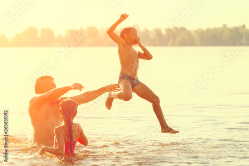 Jumping in the water. Man with children are having fun and splashing in the water. Summer holiday concept