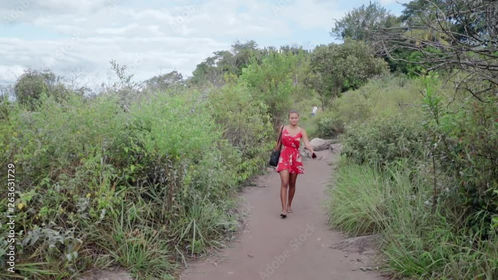Slow Motion: Woman In Red Dress Walking Down Dirt Road Surrounded By Bushes in Chapada, Brazil Slow Motion: Woman In Red Dress Walking Down Dirt Road Surrounded By Bushes in Chapada, Brazil