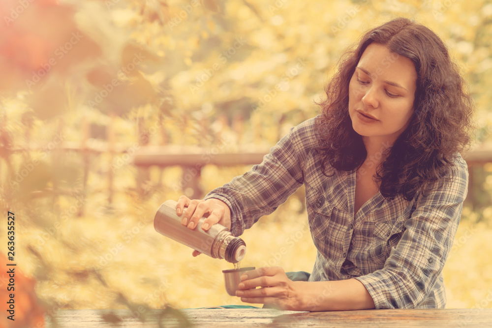 Traveling woman pours tea from a thermos Traveling woman pours tea from a thermos