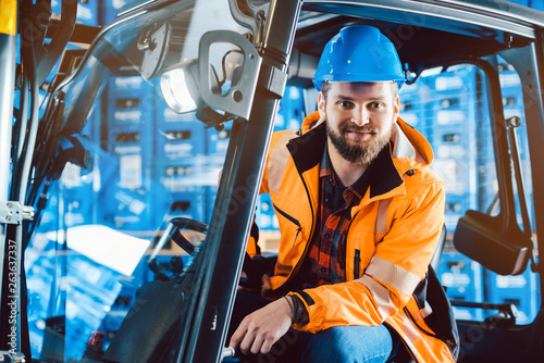 Worker in warehouse sitting in his forklift