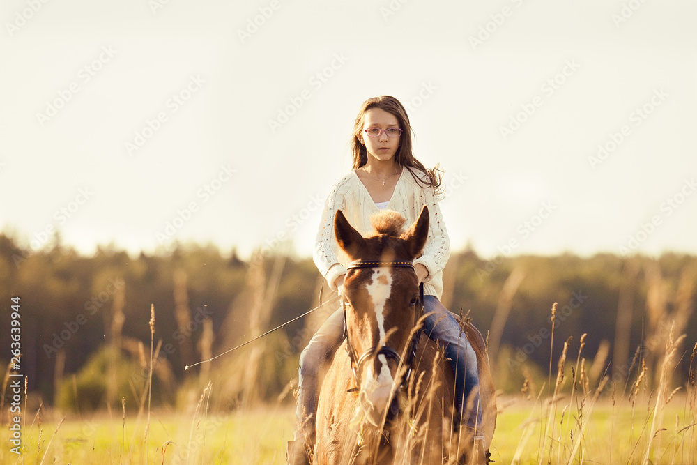 Young girl goes sorrel horse riding in field