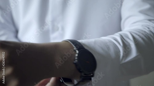 Close up of man in dress shirt putting on watch photo