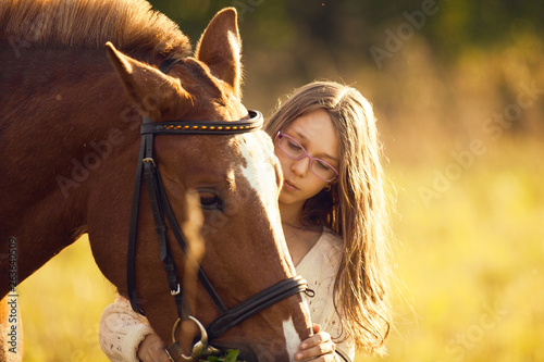 Young girl with horse in field © Olga