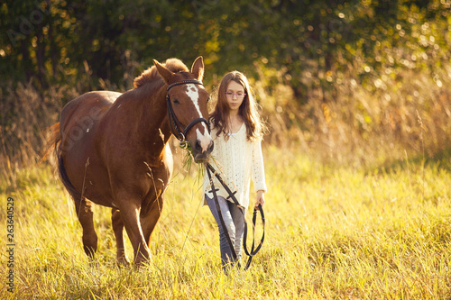 Young girl with sorrel horse in field