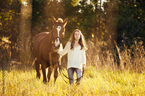 Young girl with sorrel horse in field