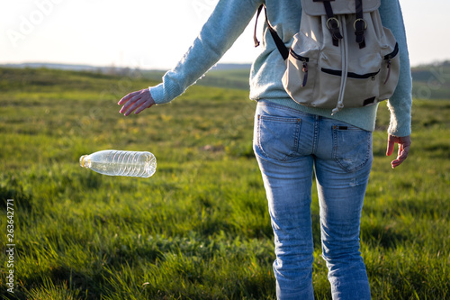 Irresponsible tourist throwing away plastic bottle in nature. Environmental damage photo