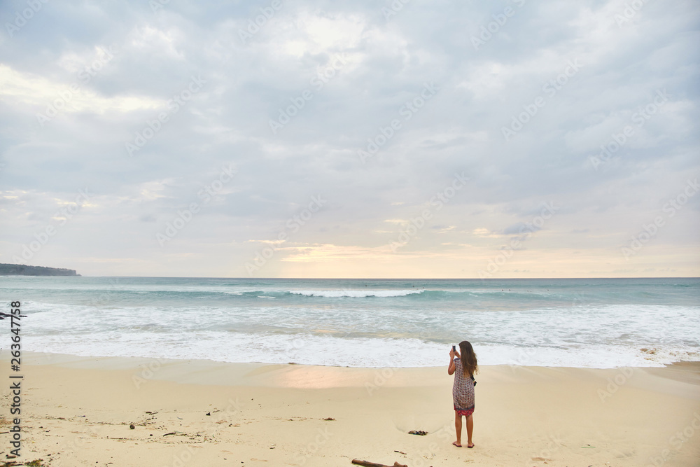 Young woman takes pictures on her phone. Girl taking pictures of a landscape.