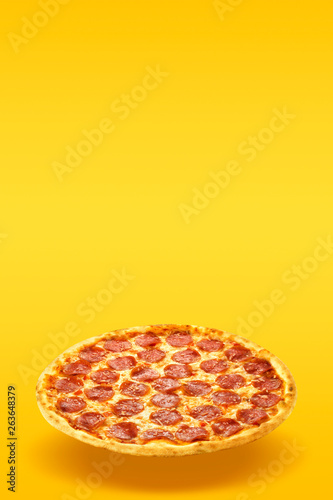 Creative layout of hot delicious pizza in flying on summer orange background. Pizza pepperoni design mockup flyer or poster for promotions and discounts with copy space. Fast Food concept