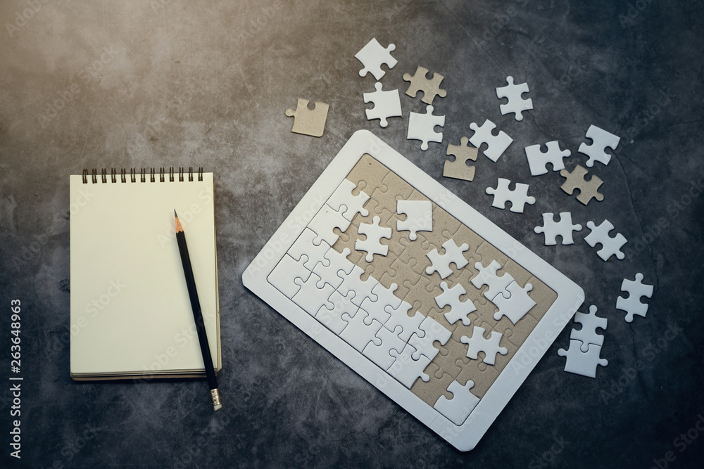 Naklejka premium Top View of jigsaw puzzle and blank notebook with pencil on black background. Business solve problem concept.
