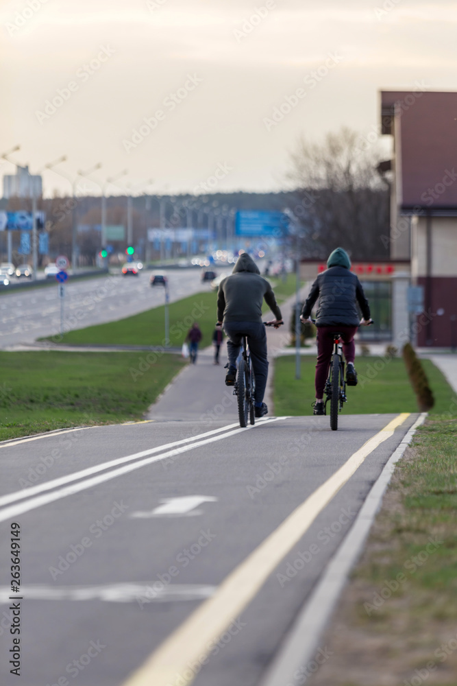 Two cyclists take a bike ride on the city bike path. Spring city evening landscape. Concept: healthy lifestyle.