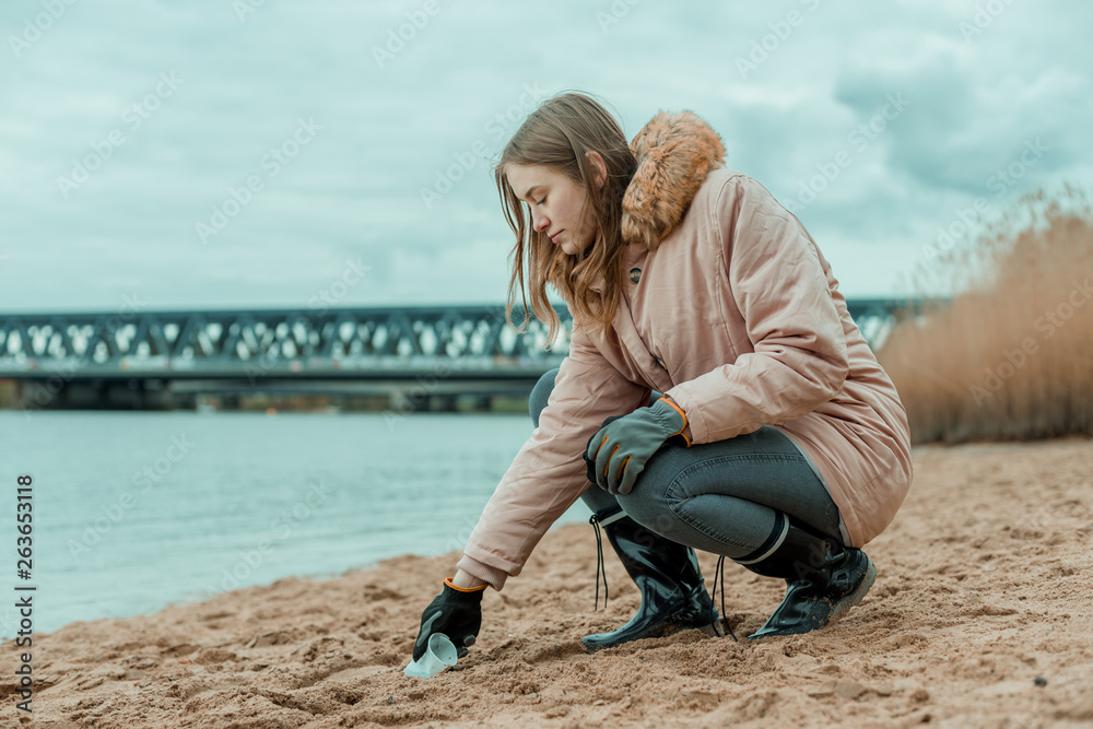 Eine junge Frau reinigt den Strand von Plastik Abfall
