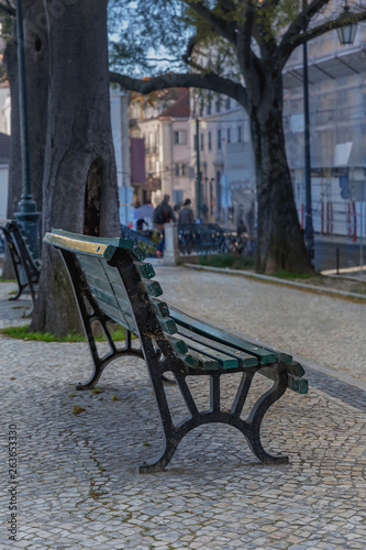 Wooden bench on a stone walkway in the city park of the Portuguese city of Porto © westermak15