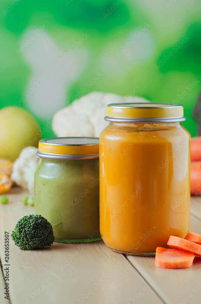 Carrot and broccoli puree in glass jars on wooden background Carrot and broccoli puree in glass jars on wooden background
