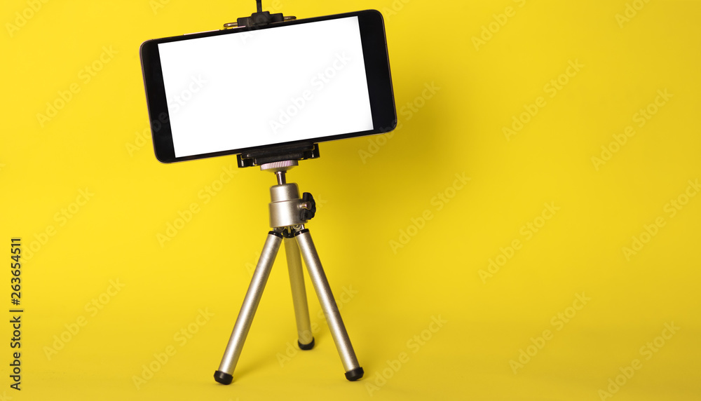 Blank phone on a tripod on a bright yellow background with copyspace. Mobile blog Blank phone on a tripod on a bright yellow background with copyspace. Mobile blog