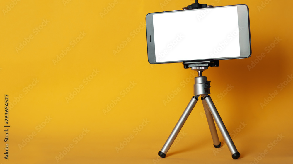 Blank phone on a tripod on a bright yellow background with copyspace. Mobile blog Blank phone on a tripod on a bright yellow background with copyspace. Mobile blog
