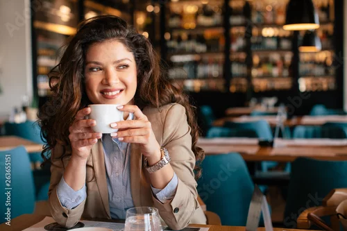 Fototapeta Young woman is drinking coffee in a cafe