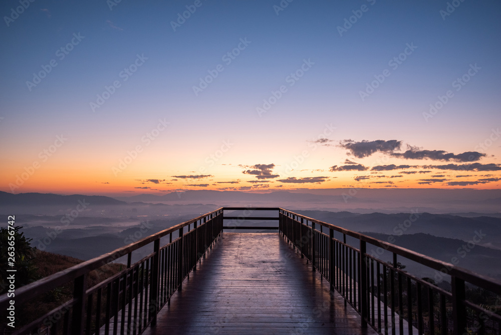 rising sun in the morning on top of the hill with wooden pathway ahead to sunrise.Success concept