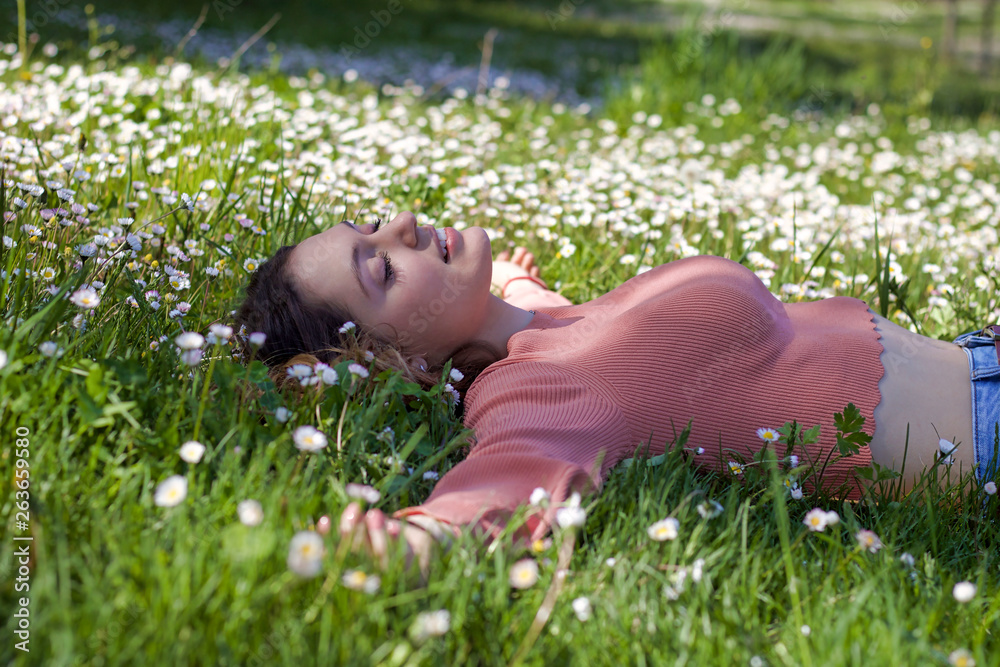 beautiful woman whith open arms smiling lying on a carpet of daisies beautiful woman whith open arms smiling lying on a carpet of daisies