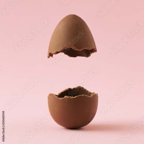 Fotobehang Chocolate Easter egg broken in half on pastel pink background with creative copy space
