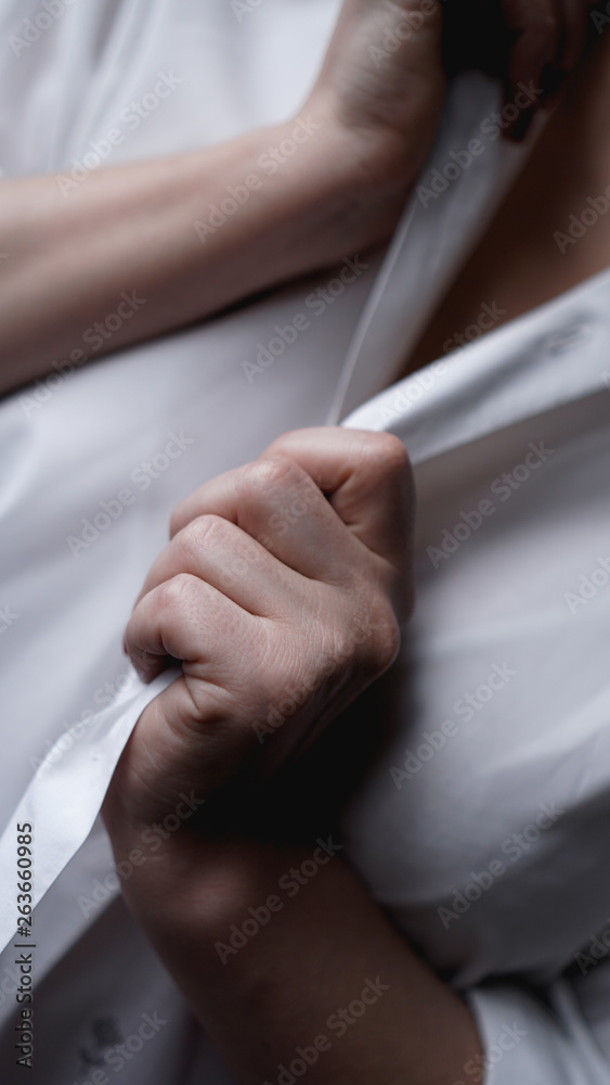 A woman holds her hands for a mens white shirt. Photo without face A woman holds her hands for a mens white shirt. Photo without face