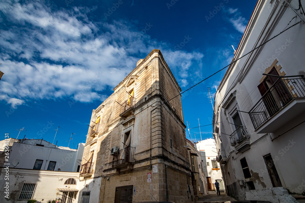 Beautiful facade of building in Puglia. Mediterranean architecture of Southern Italy. Scenery summer blue-sky day with expressive clouds. Day street alleyway view, European travel photography