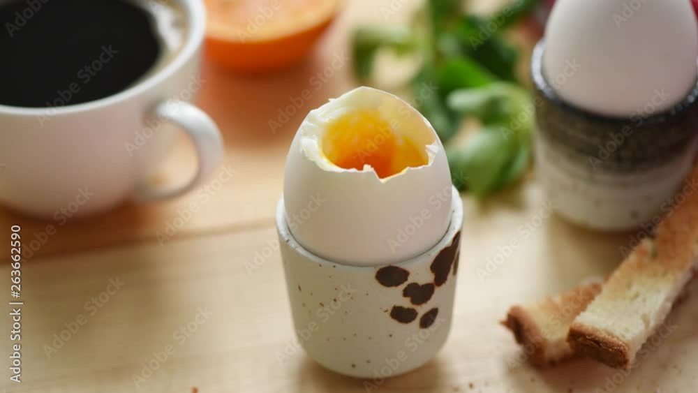 Eating soft boiled egg with toasted bread. Someone dipping bread into egg yolk. Breakfast time