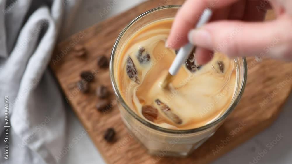 Slow motion of mixing ice coffee with cream, closeup view