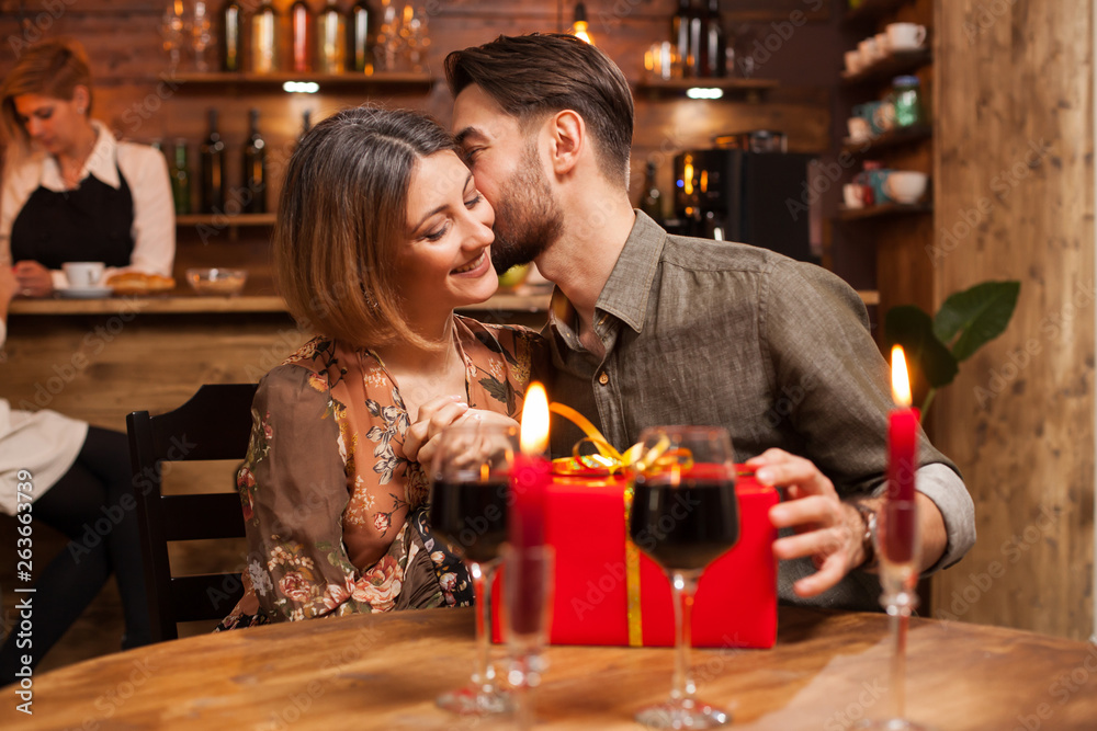 Attractive bearded man kissing his girlfriend cheek after recieving a birthday gift