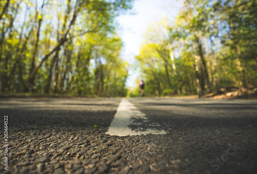 Fototapeta Naklejka Na Ścianę i Meble -  Trip or adventure: Closeup perspective of a street, forest in the blurry background
