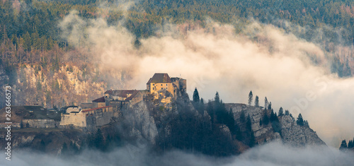 Le Château de Joux entouré de brume matinale