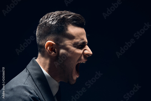 Fototapeta Naklejka Na Ścianę i Meble -  Profile view of angry disappointment man shouting with copy space isolated on dark background