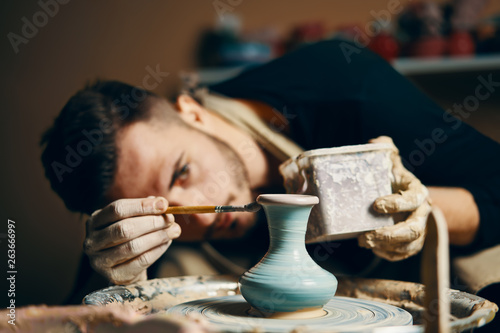 Man painting handmade pottery at ceramic workshop photo